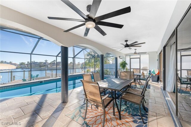 sunroom featuring ceiling fan, a pool, and a water view