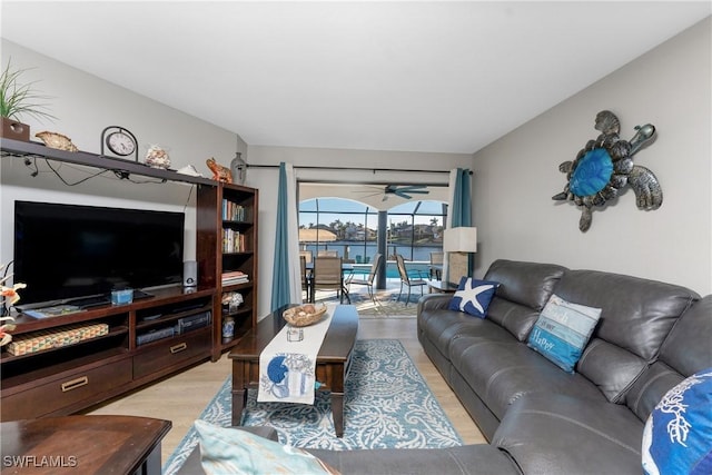 living room featuring ceiling fan, a water view, and light hardwood / wood-style floors