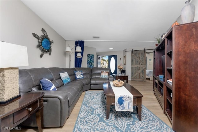 living room featuring a barn door and light hardwood / wood-style floors