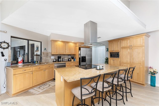 kitchen featuring sink, a kitchen island, light stone counters, island exhaust hood, and stainless steel appliances