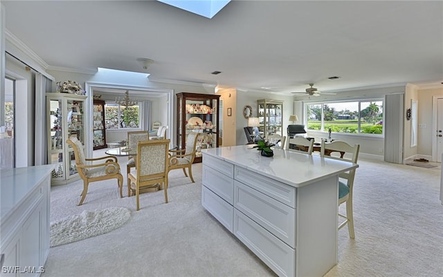 kitchen featuring a breakfast bar, ceiling fan with notable chandelier, light colored carpet, a kitchen island, and white cabinetry