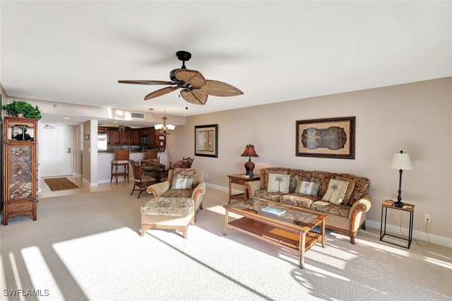 carpeted living room with ceiling fan with notable chandelier