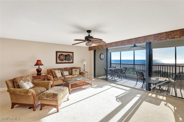 living room with ceiling fan, a water view, and light carpet