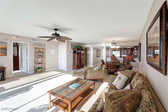 carpeted living room featuring ceiling fan with notable chandelier