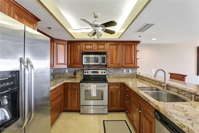 kitchen with kitchen peninsula, appliances with stainless steel finishes, light stone counters, and sink