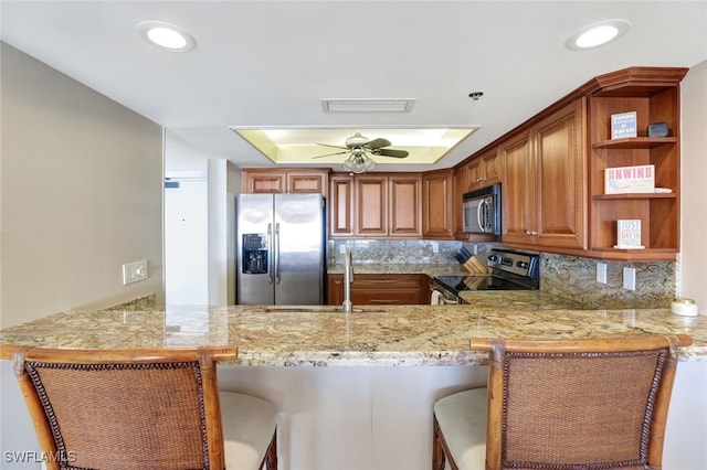 kitchen with kitchen peninsula, appliances with stainless steel finishes, a kitchen breakfast bar, and sink