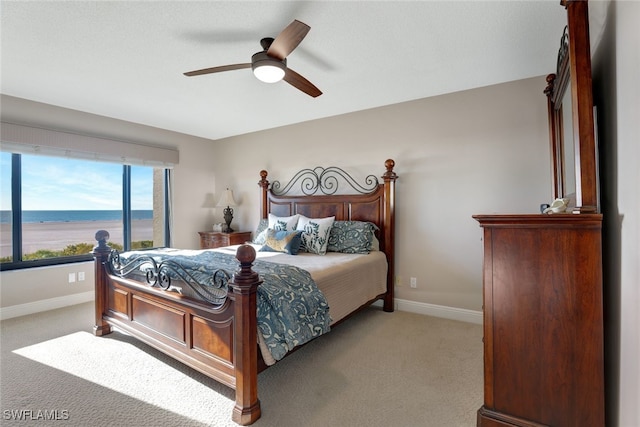 carpeted bedroom featuring a water view and ceiling fan