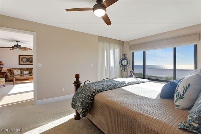 carpeted bedroom with ceiling fan and a water view