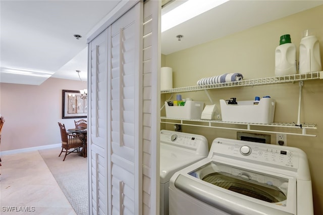 washroom featuring washing machine and dryer, light colored carpet, and an inviting chandelier