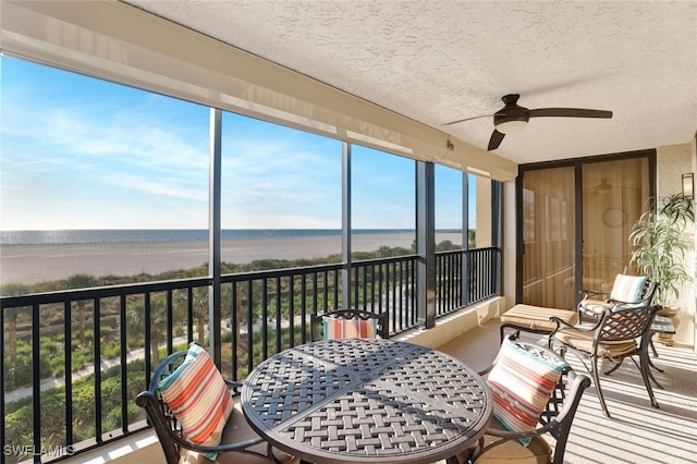 sunroom featuring a water view and ceiling fan