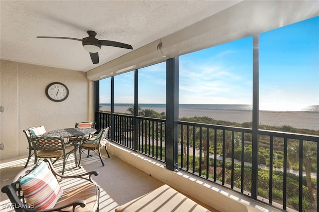 sunroom featuring ceiling fan and a water view