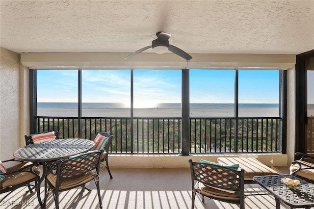 sunroom / solarium with a water view and ceiling fan