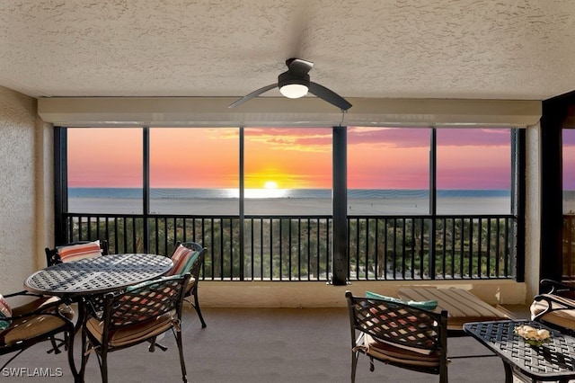 sunroom with a wealth of natural light, a water view, and ceiling fan