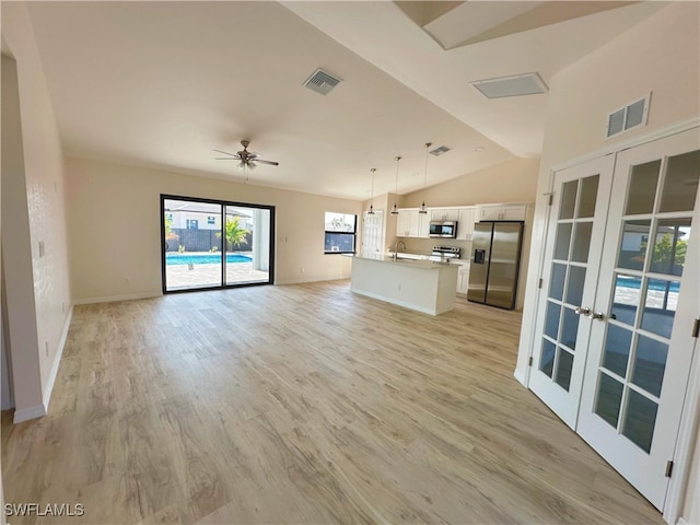 unfurnished living room with ceiling fan, french doors, sink, light hardwood / wood-style floors, and vaulted ceiling