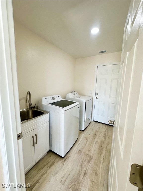 laundry room with washer and dryer, light wood-type flooring, and sink