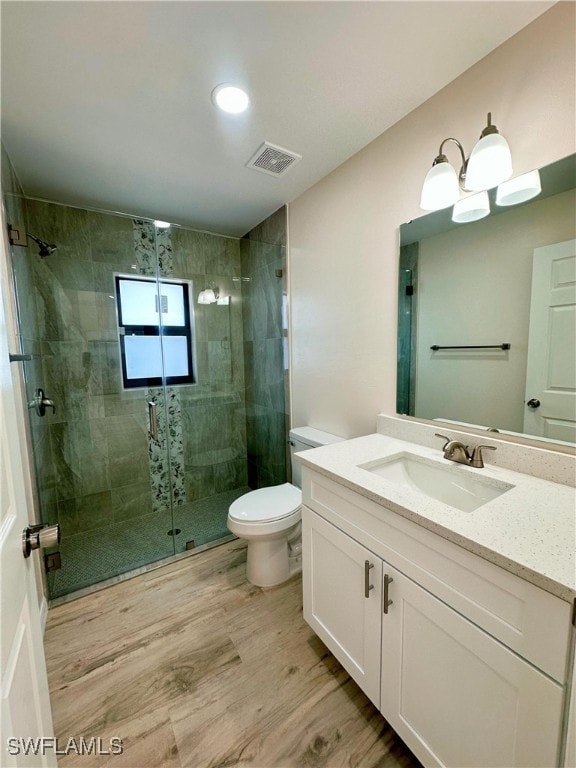 bathroom featuring vanity, hardwood / wood-style flooring, toilet, and a shower with shower door