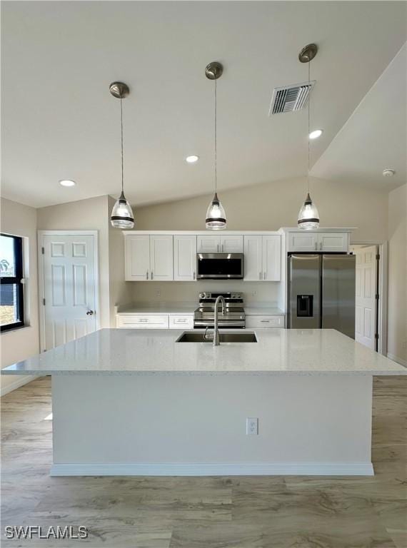 kitchen featuring white cabinets, pendant lighting, stainless steel appliances, and light stone countertops