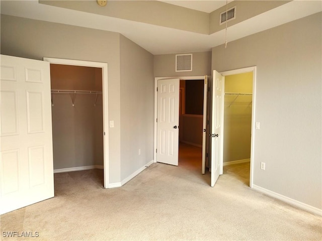 unfurnished bedroom with light colored carpet and a spacious closet