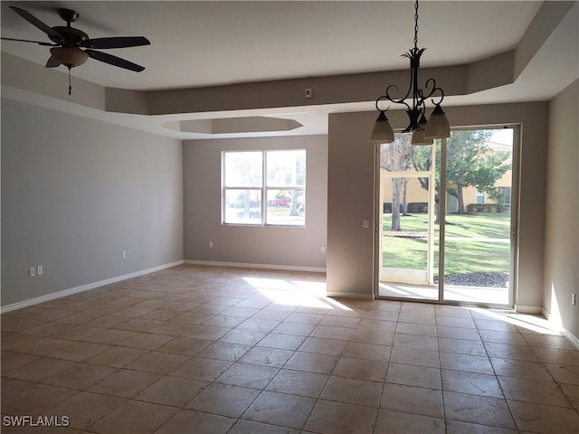 empty room featuring a tray ceiling, light tile patterned floors, and ceiling fan with notable chandelier