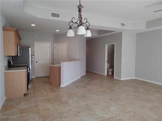 kitchen featuring a raised ceiling, pendant lighting, a notable chandelier, and range