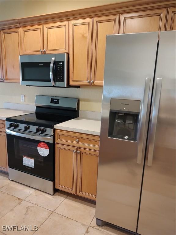 kitchen featuring stainless steel appliances and light tile patterned flooring