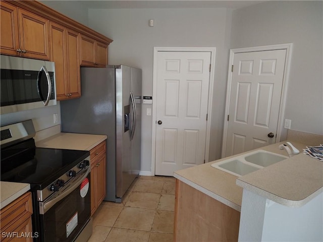 kitchen featuring kitchen peninsula, light tile patterned floors, stainless steel appliances, and sink