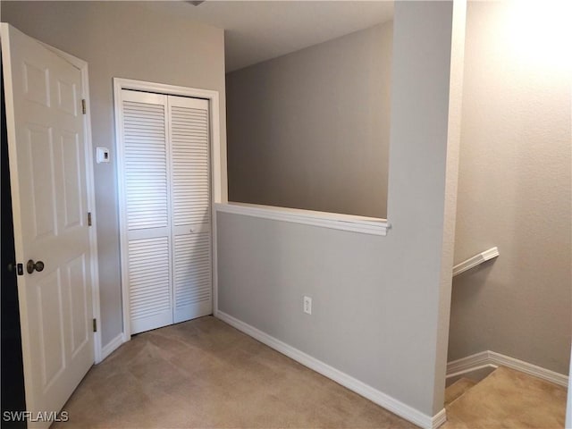 unfurnished bedroom featuring light carpet and a closet