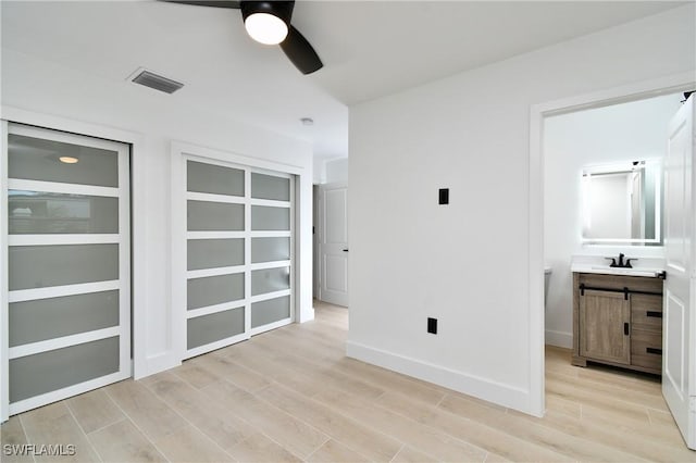 empty room with ceiling fan, sink, and light hardwood / wood-style floors