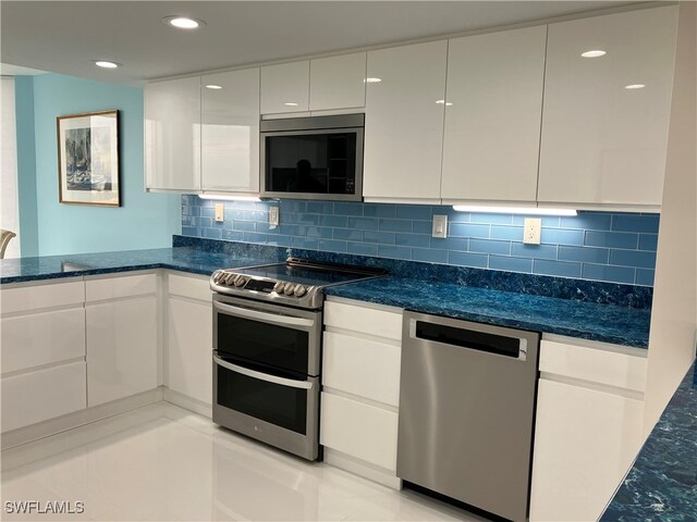 kitchen featuring white cabinets, dark stone countertops, light tile patterned floors, and appliances with stainless steel finishes