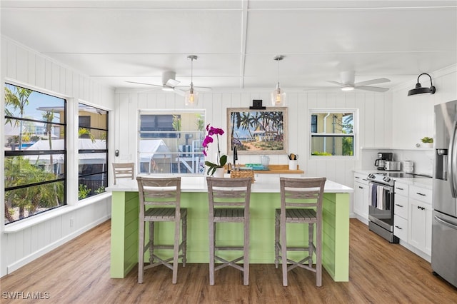 kitchen featuring stainless steel appliances, white cabinetry, a kitchen island with sink, and a kitchen bar