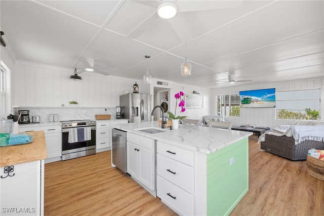 kitchen with stainless steel appliances, white cabinetry, a center island with sink, and ceiling fan