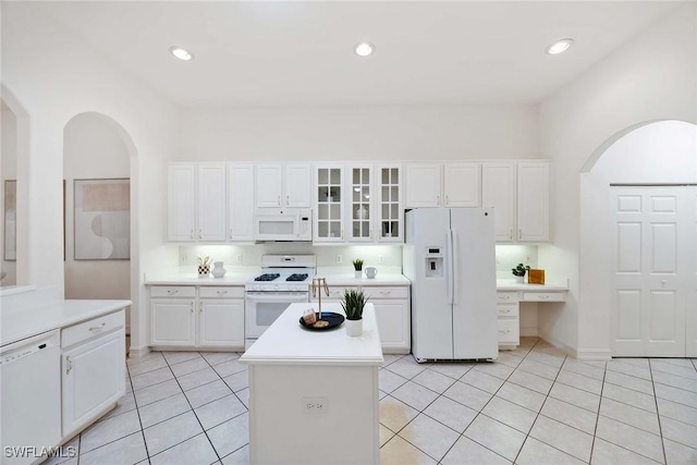 kitchen with white cabinets, white appliances, a kitchen island, and light tile patterned flooring