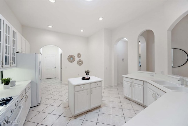 kitchen featuring stove, white cabinets, sink, light tile patterned floors, and a kitchen island