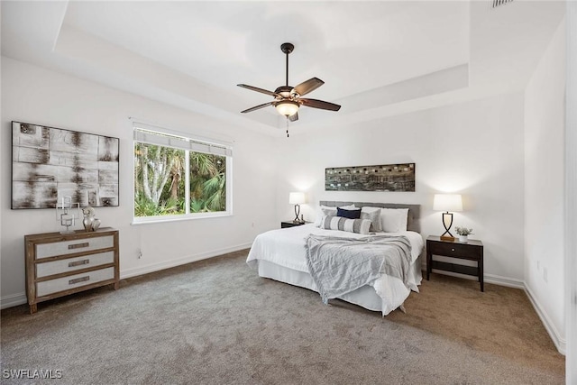 carpeted bedroom with a tray ceiling and ceiling fan