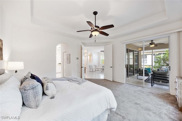 carpeted bedroom featuring a raised ceiling, ceiling fan, and access to outside