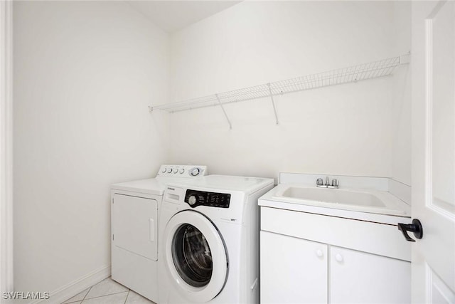 laundry area with washing machine and dryer, sink, light tile patterned floors, and cabinets