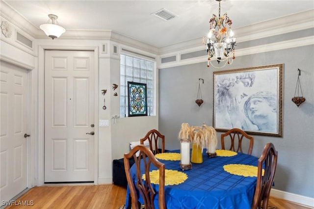 dining area with hardwood / wood-style flooring, crown molding, and a chandelier