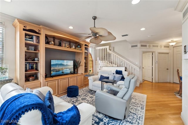 living room featuring built in shelves, ceiling fan, light hardwood / wood-style flooring, and crown molding