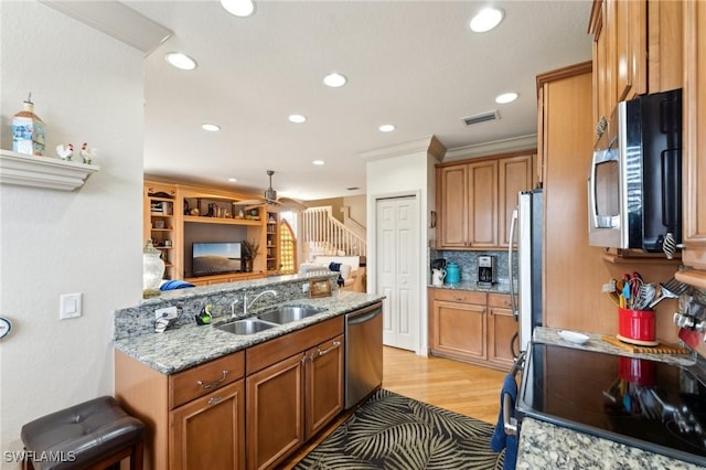 kitchen featuring light stone countertops, appliances with stainless steel finishes, crown molding, and sink