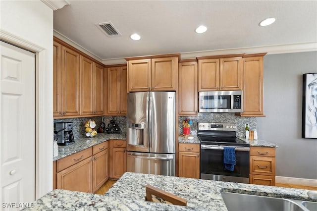 kitchen featuring light stone counters, backsplash, and appliances with stainless steel finishes