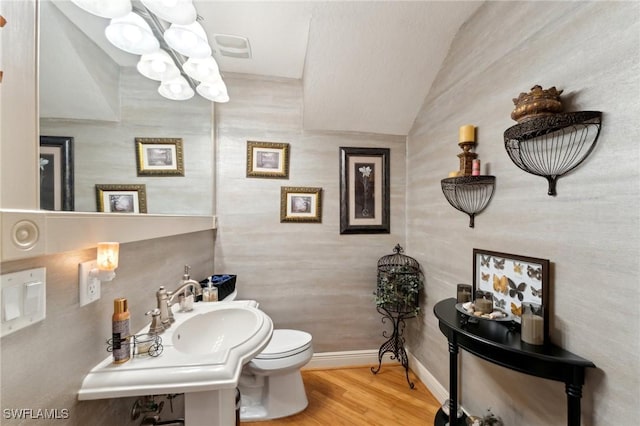 bathroom featuring hardwood / wood-style floors, vaulted ceiling, and toilet