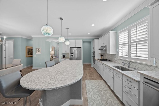 kitchen featuring sink, decorative backsplash, decorative light fixtures, a kitchen island, and stainless steel appliances