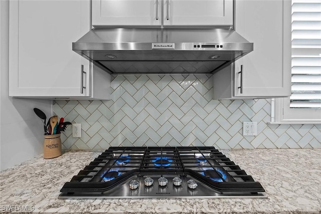 kitchen with backsplash, white cabinetry, exhaust hood, and stainless steel gas cooktop