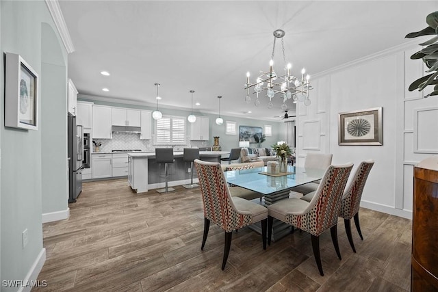 dining room featuring light wood-type flooring, ceiling fan with notable chandelier, and ornamental molding