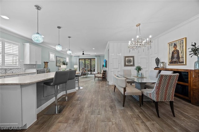 dining space featuring hardwood / wood-style floors, ceiling fan with notable chandelier, and crown molding