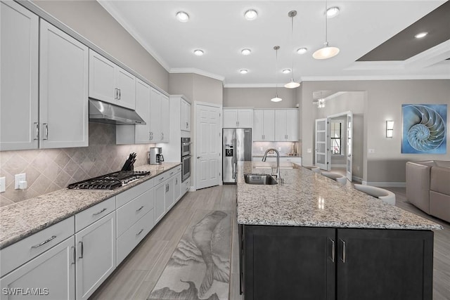 kitchen featuring appliances with stainless steel finishes, sink, a large island with sink, pendant lighting, and white cabinets