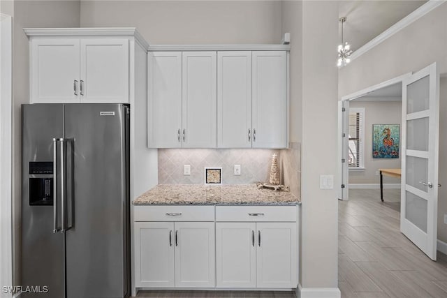 kitchen featuring white cabinetry, high end refrigerator, tasteful backsplash, and light stone counters