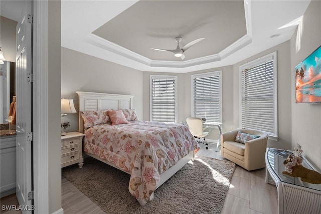 bedroom featuring a tray ceiling, ceiling fan, crown molding, and light hardwood / wood-style flooring