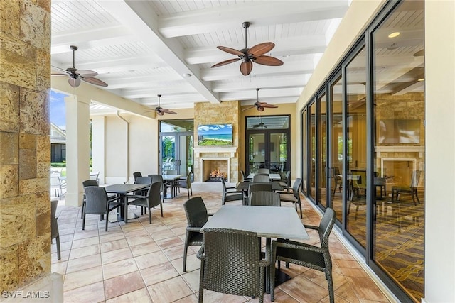 interior space with ceiling fan, a fireplace, beamed ceiling, and french doors