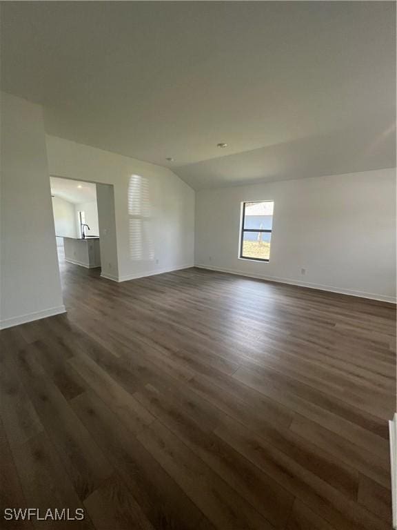 spare room featuring dark hardwood / wood-style floors and vaulted ceiling